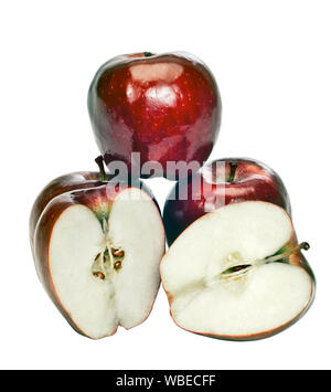 Shot verticale de quatre pommes d'un rouge brillant sur un fond blanc. Un identifiant Apple est équilibrée des deux autres. La quatrième coupe d'apple a été ouverte et est en face Banque D'Images