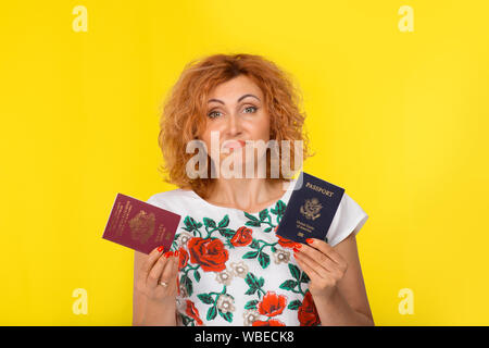 Je ne sais pas qui la citoyenneté à choisir concept. Portrait Jeune femme tenant deux passeports un Européen et Américain rouge bourgogne bleu confondu f Banque D'Images