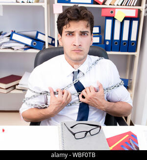 L'employé attaché et enchaîné à son bureau avec chaîne Banque D'Images