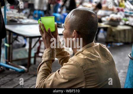 Mendiant mendicité et holding cup pour les dons. La Thaïlande Asie du sud-est Banque D'Images