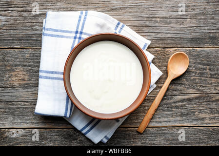 Dans un bol de yogourt grec sur table en bois avec une cuillère de bois. Vue d'en haut. Produits laitiers sains riche en calcium et en protéines Banque D'Images