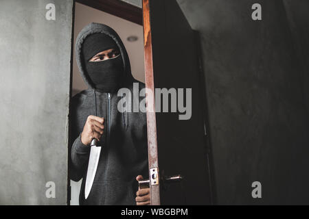 Le voleur est titulaire d'un couteau pour ouvrir la porte de la maison pour vol qualifié. Banque D'Images