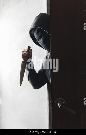 Le voleur est titulaire d'un couteau pour ouvrir la porte de la maison pour vol qualifié. Banque D'Images