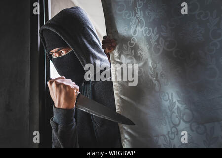 Le voleur est titulaire d'un couteau pour ouvrir la porte de la maison pour vol qualifié. Banque D'Images