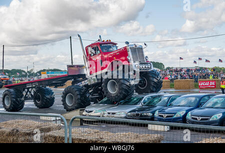 Le grand Pete monster truck écraser une pile de carcasses de voitures en tirant sa remorque sur mesure au cours d'une manifestation à un monster truck show Banque D'Images