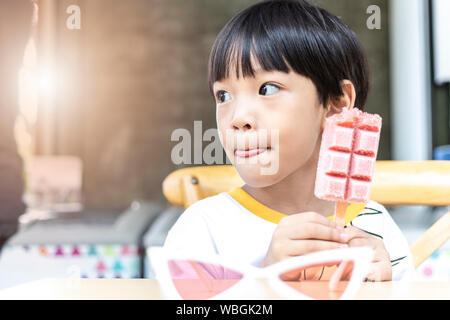 Asian cute little boy eating strawberry ice cream stick Banque D'Images