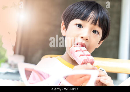 Asian cute little boy eating strawberry ice cream stick Banque D'Images