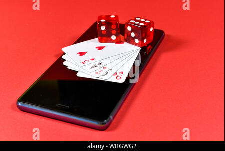 Téléphone mobile sur fond rouge avec plusieurs jeux de cartes et de dés rouge sur l'affichage de l'image conceptuelle, à propos de l'industrie du jeu mobile Banque D'Images