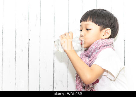 Cute asian petit enfant boire de l'eau dans le verre. Portrait of boy main tenant l'eau potable. Banque D'Images