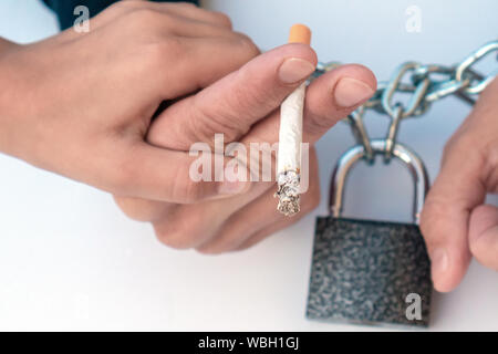 La femme, les mains liées par les chaînes et verrouiller avec la cigarette sur un fond blanc. La main de l'enfant indique 'Do pas fumer, maman". Arrêter de fumer la cigarette, concept Banque D'Images