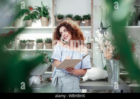 Cheerful fille rousse écrire les informations dans l'ordinateur portable Banque D'Images