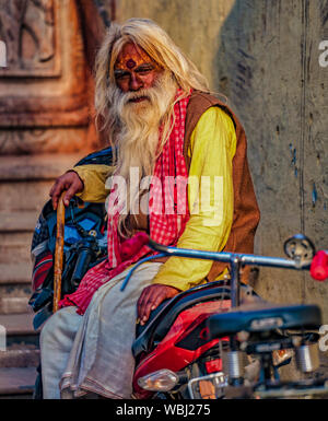 Vrindavan, Inde - 22 février 2018 - vieil homme est assis sur une moto tout en tenant une canne en bois Banque D'Images