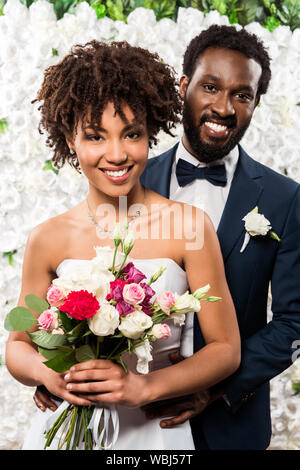 Cheerful african american bride holding bouquet de fleurs près de l'epoux Banque D'Images