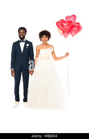 Cheerful african american époux tenant la main avec happy bride avec des ballons isolated on white Banque D'Images