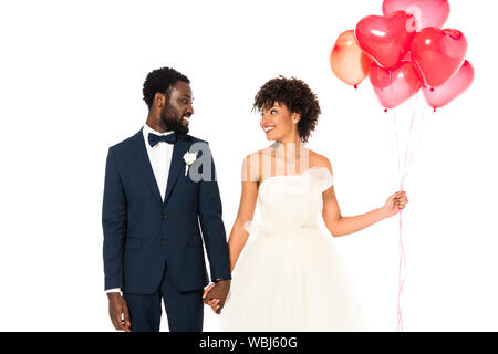 Cheerful african american époux tenant la main avec de jolis ballons mariée près de isolated on white Banque D'Images
