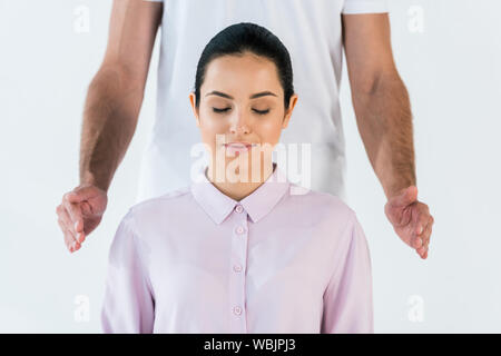 Portrait de guérisseur mettant les mains près de belle femme aux yeux clos isolated on white Banque D'Images