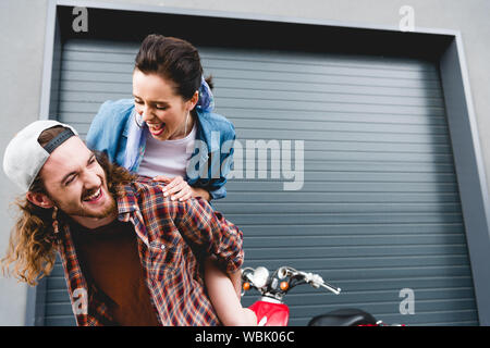 Jeune homme et la jeune fille riant, greffant debout près de red scooter Banque D'Images