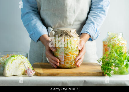 Préservation de la fermentation de la choucroute dans des bocaux en verre dans les mains d'une femme dans le milieu naturel. Traitement de la chasse d'automne. Copier l'espace. Ve en conserve Banque D'Images