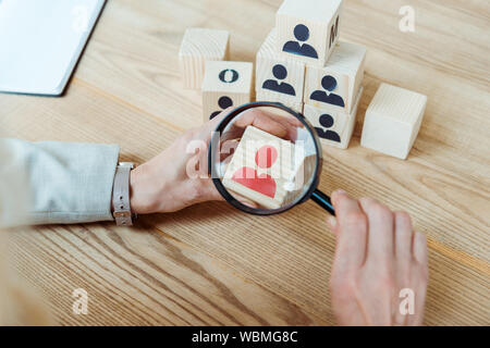 Portrait de femme tenant magnifier près de cube de bois Banque D'Images