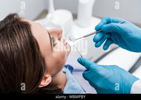 Portrait de l'homme dans des gants en latex holding instruments dentaires près de belle femme Banque D'Images