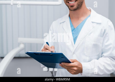 Portrait of happy doctor holding clipboard barbu et stylo en clinique Banque D'Images