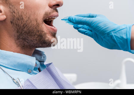 Portrait de dentiste en tenant près de retenue de gants en latex homme avec bouche ouverte Banque D'Images