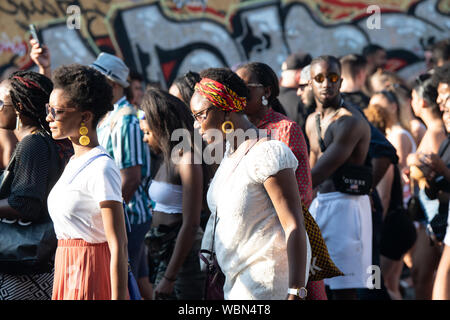 Deux femmes noires, marchant à travers la foule à Notting Hill Carnival against white tops et jaune boucles d'oreille. Banque D'Images