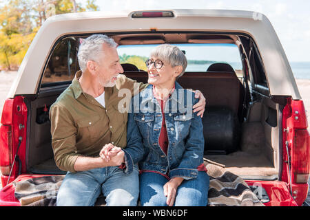 Smiling senior couple embracing, près de voiture Banque D'Images
