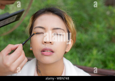 Gros plan d'une femme modèle asiatique tout en appliquant le maquillage pour les yeux fermés Banque D'Images