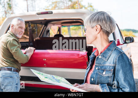 Man près de voiture rouge tout en wife holding la carte en journée ensoleillée Banque D'Images