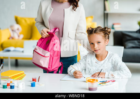 Portrait de mère tenant près de sac à dos fille mignon à la maison de peinture Banque D'Images