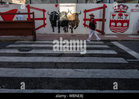 San Sebastian de los Reyes, Madrid, Espagne. 27 août 2019. Un homme passe par un mur décoré avec les taureaux avant le début de la première course de taureaux aussi connu comme 'peu de Pampelune". Credit : Marcos del Mazo/Alamy Live News Banque D'Images