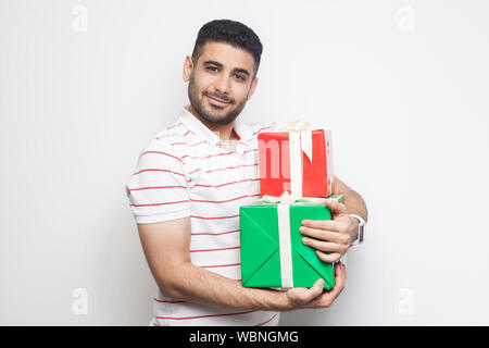 Portrait of happy satisfait beau jeune homme barbu adultes en t-shirt blanc debout et tenant deux présent fort et s'étreindre. Piscine, isolée, s Banque D'Images