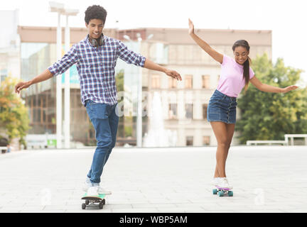 Les adolescents gais racing sur skateboards contre cityscape Banque D'Images