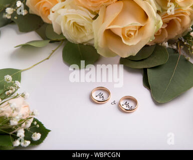 Les anneaux de mariage avec texte à l'intérieur sur l'arrière-plan avec des roses crème Banque D'Images