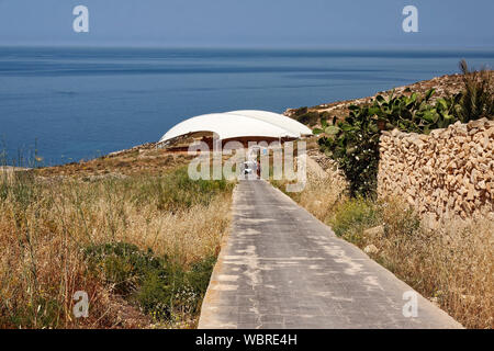 Ruines du temple de Mnajdra neolithic ; revêtement de protection, mer Méditerranée ; chemin pavé, les gens marcher, chariot de golf, les transports ; l'Europe ; de Qrendi Malte ; s Banque D'Images