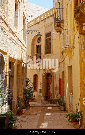 Rue piétonne étroite, de city scene ; vieux bâtiments en pierre calcaire ; petits balcons, plantes en pot, attrayant, soleil, ombre, Europe, Birgu, Vittoriosa, Malt Banque D'Images