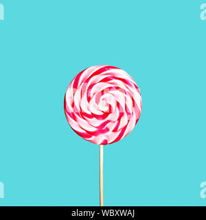 Sucette coloré rouge et rose sur fond bleu pastel. Sweet sugar candy tourbillonner dans la mode moderne style. Un minimum de mise à plat design. La nourriture pour les enfants Banque D'Images