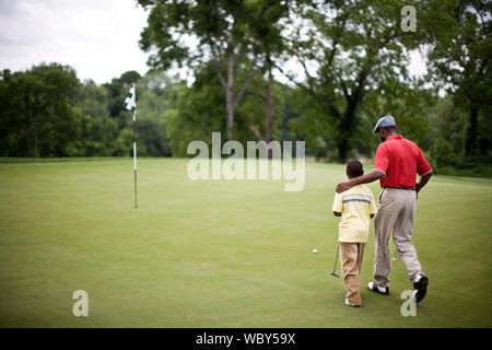 Père et fils marchant sur un terrain de golf Banque D'Images