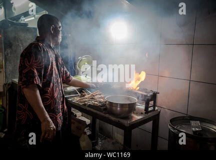 Un gars sur un gril barbecue feu satay. Banque D'Images