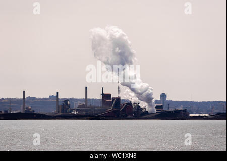 HAMILTON, ONTARIO, CANADA - 21 avril 2018 : un grand panache de vapeur est à la dérive est libéré à une usine d'acier sur la rive du port de Hamilton. Banque D'Images