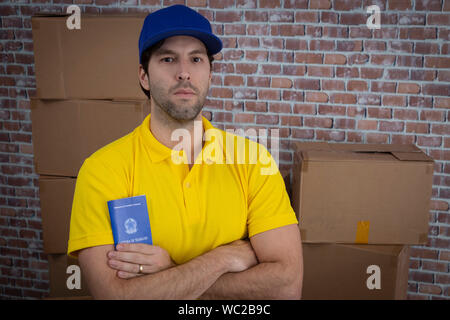 Mailman brésilien tenant son carnet de travail sécurité sociale brésilienne document, dans un dépôt avec un beaucoup de boîtes. Banque D'Images