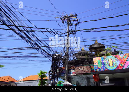 Legian, Bali, Indonésie - Août 13, 2018 : les fils électriques malpropre et telecom accrochée au-dessus d'une rue à Legian, Indonésie. Banque D'Images