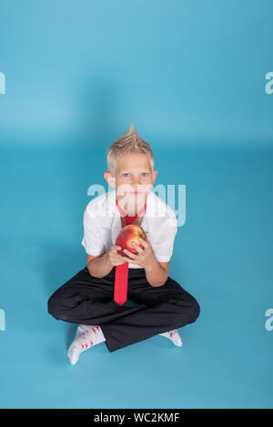 Close-up d'un garçon blond.Le garçon pose sur l'appareil photo. Il est charmant.petit écolier.Professeur dans une école uniforme avec une chemise blanche et noire pa Banque D'Images