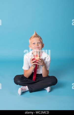 Close-up d'un garçon blond.Le garçon pose sur l'appareil photo. Il est charmant.petit écolier.Professeur dans une école uniforme avec une chemise blanche et noire pa Banque D'Images