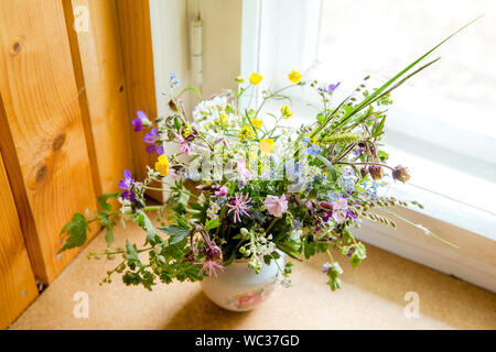 Style Vintage flower bouquet fait de fleurs sauvages trouvés en forêt et prairie, debout dans le vieux pot de crème sur le rebord de fenêtre, l'été dans la maison de grand maman con Banque D'Images