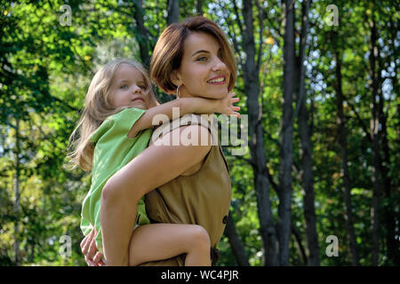 Le bonheur de la famille. Jeune fille à cheval sa maman est de retour, sur la nature dans le parc. Fille maman Concept Banque D'Images