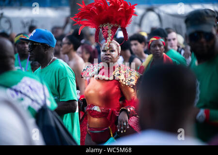 Une femme noire au Notting Hill Carnival portant une tête rouge robe faite de plumes. Banque D'Images