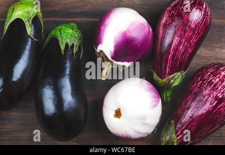 Aubergines fraîches de différentes couleur et variété sur un fond de bois Banque D'Images