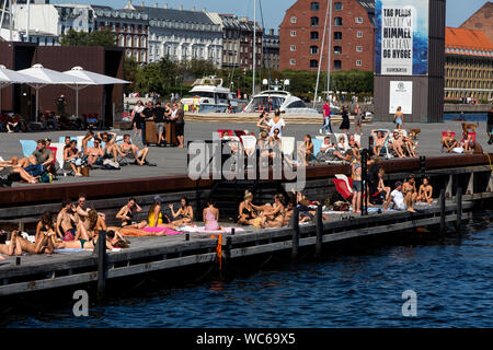 Copenhague et les touristes à l'embarcadère en bois d'Ofelia Beach près du Royal Play House et de l'historique Nyhavn à Copenhague, Danemark. L'eau dans le port de Copenhague est si propre qu'il est sûr de prendre un plongeon. En 2018, Copenhague a été en tête de liste de CNN pour les « meilleures villes pour nager ». Banque D'Images